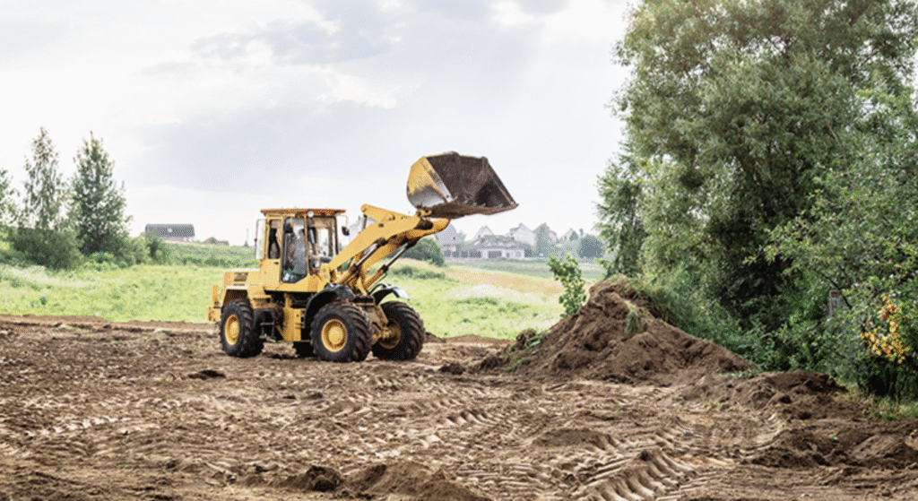 A yellow bulldozer drives along a dirt road, showcasing its powerful build and rugged terrain capability.