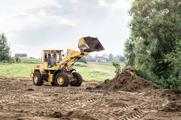 A yellow bulldozer drives along a dirt road, showcasing its powerful build and rugged terrain capability.